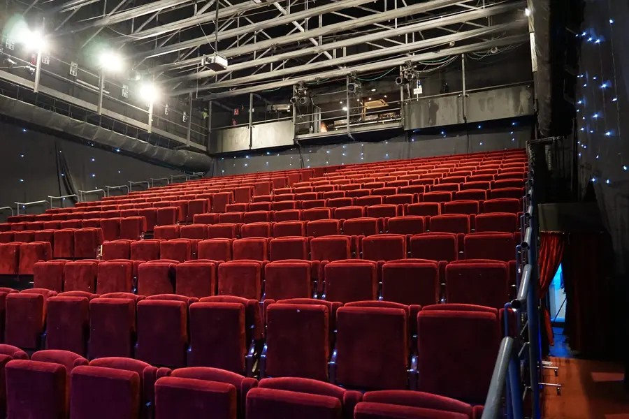 Bancada de cadeiras vermelhas num pavilhão às escuras