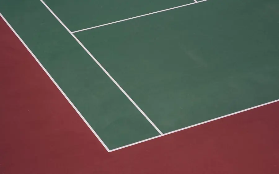 Linhas brancas de marcação num piso desportivo verde e vermelho